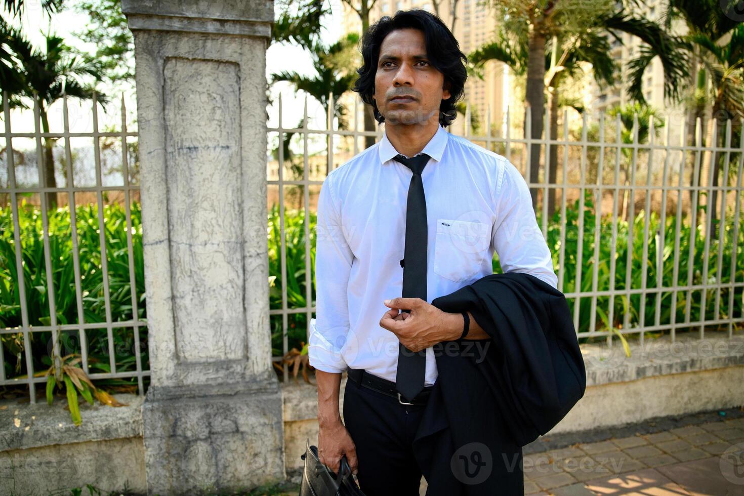 Businessman standing outdoors with jacket and briefcase photo