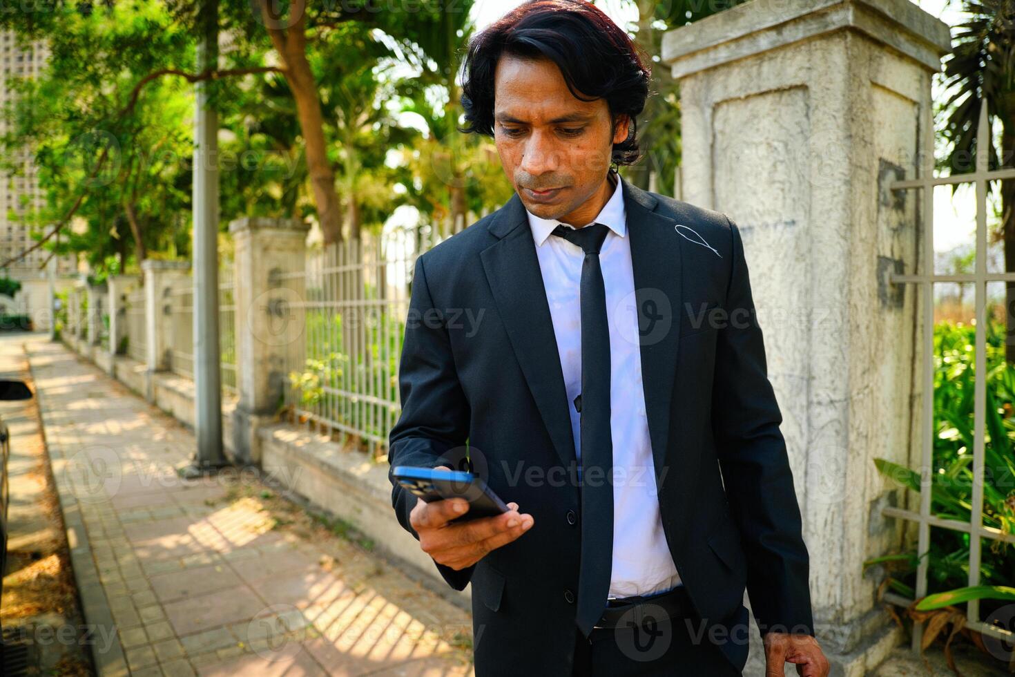 Businessman walking and using smart phone photo
