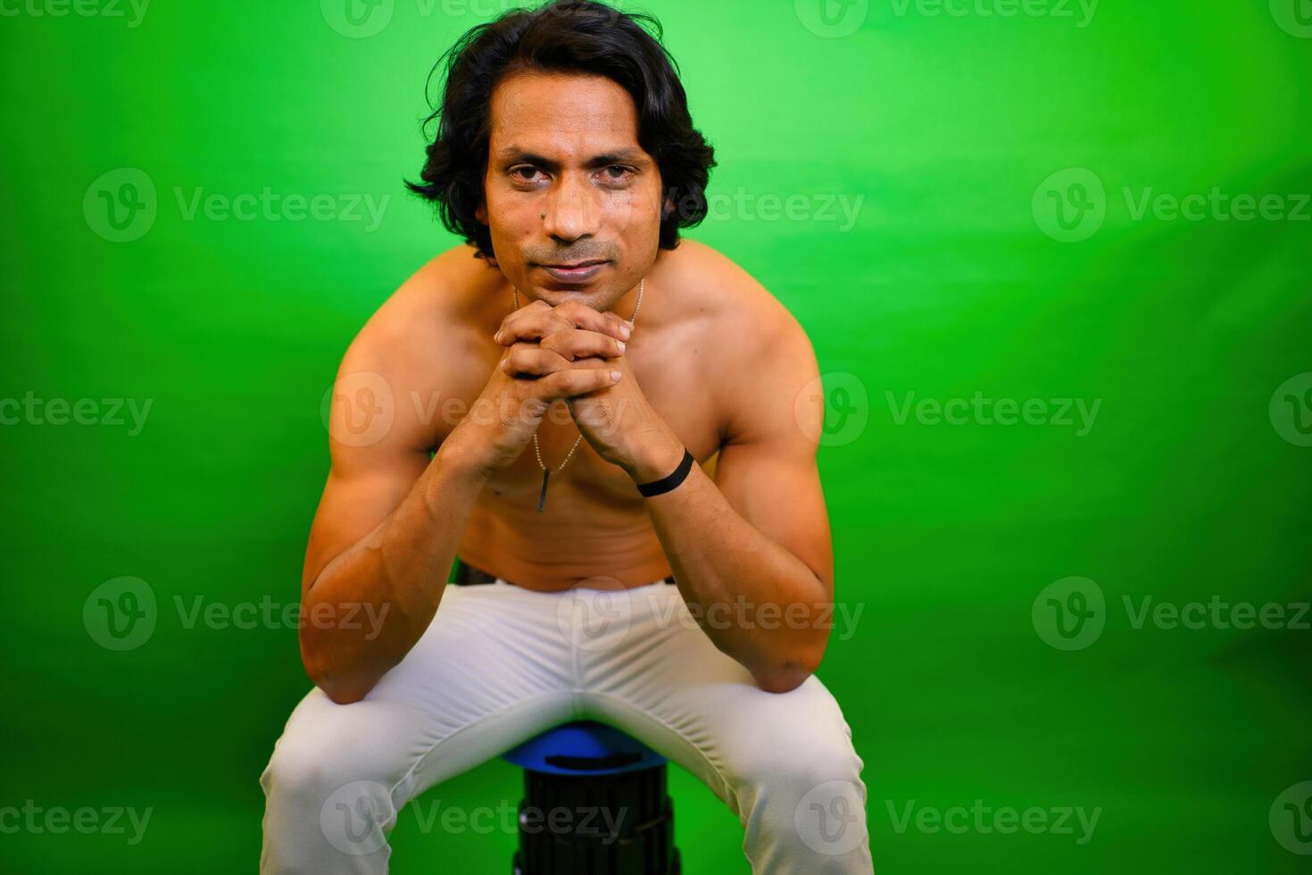 Shirtless man sitting with hand on chin photo