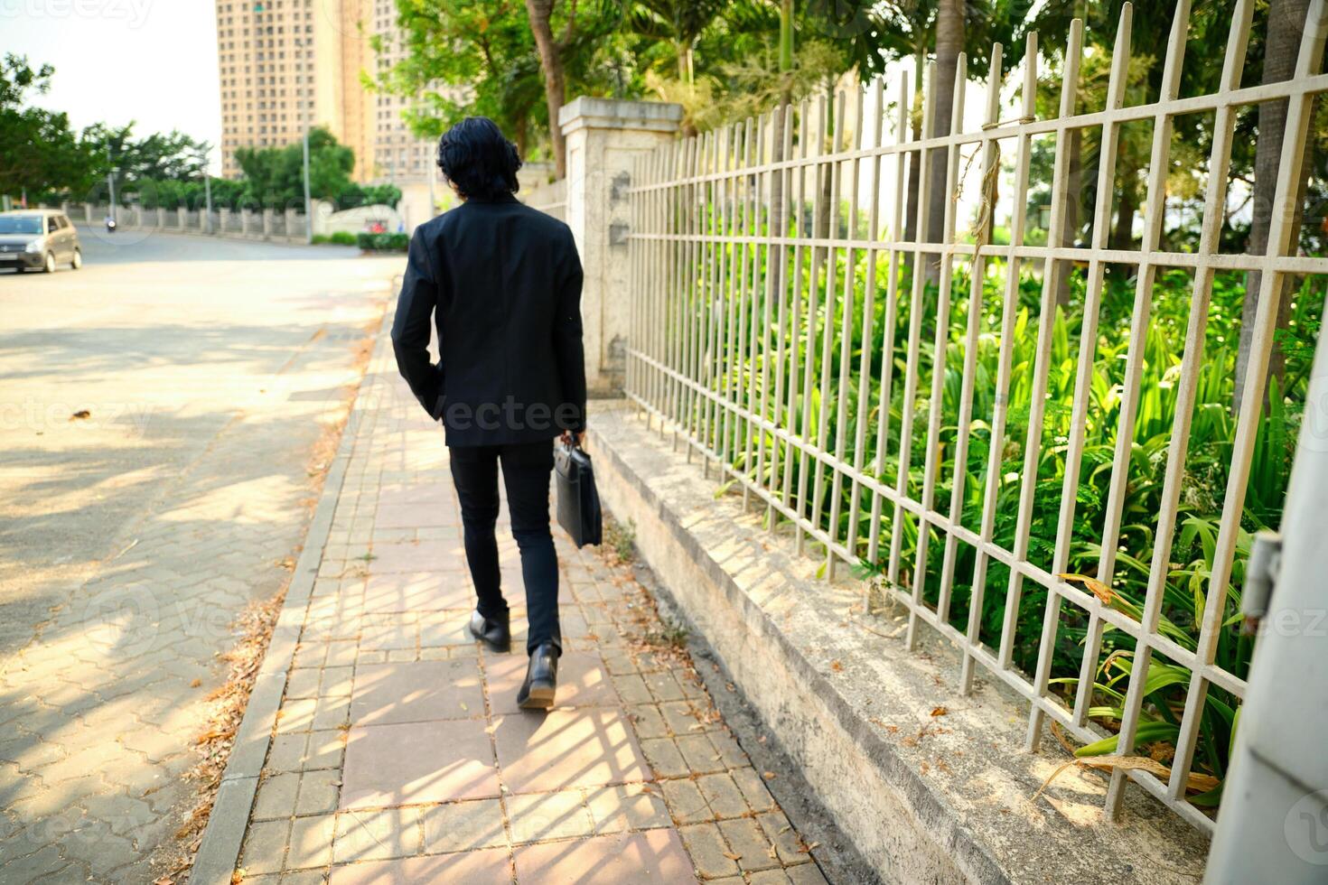 Man in black suit walking on sidewalk with briefcase photo