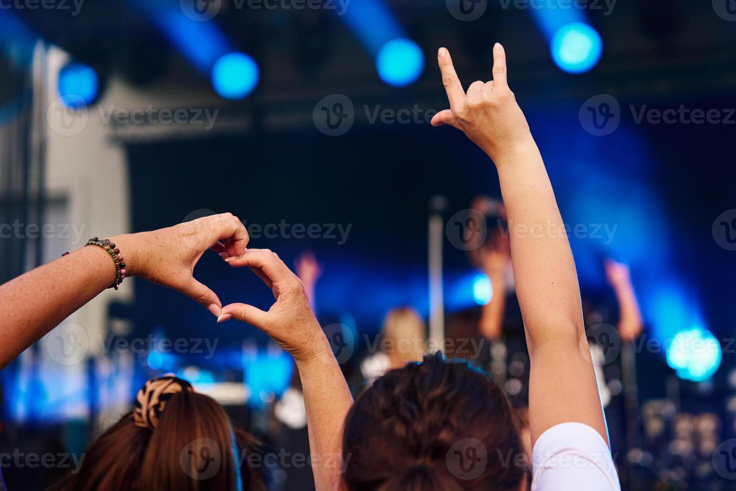 Crowd of people enjoying concert before stage with bright spotlights photo