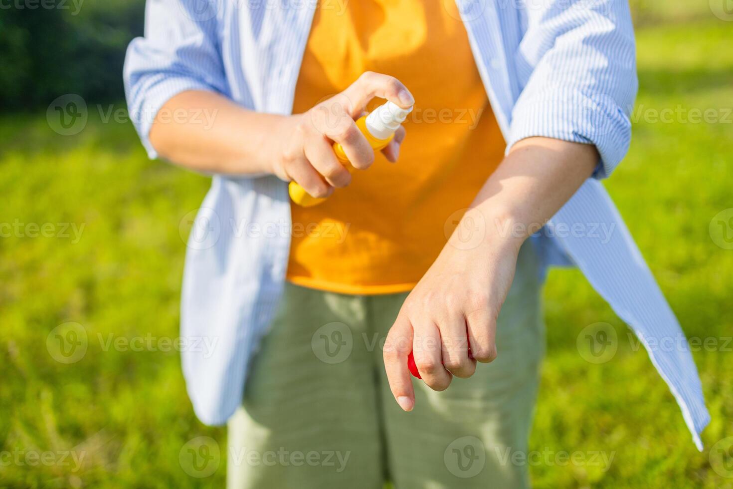 Mosquito repellent. Woman using insect repellent spray outdoors at summer park. photo