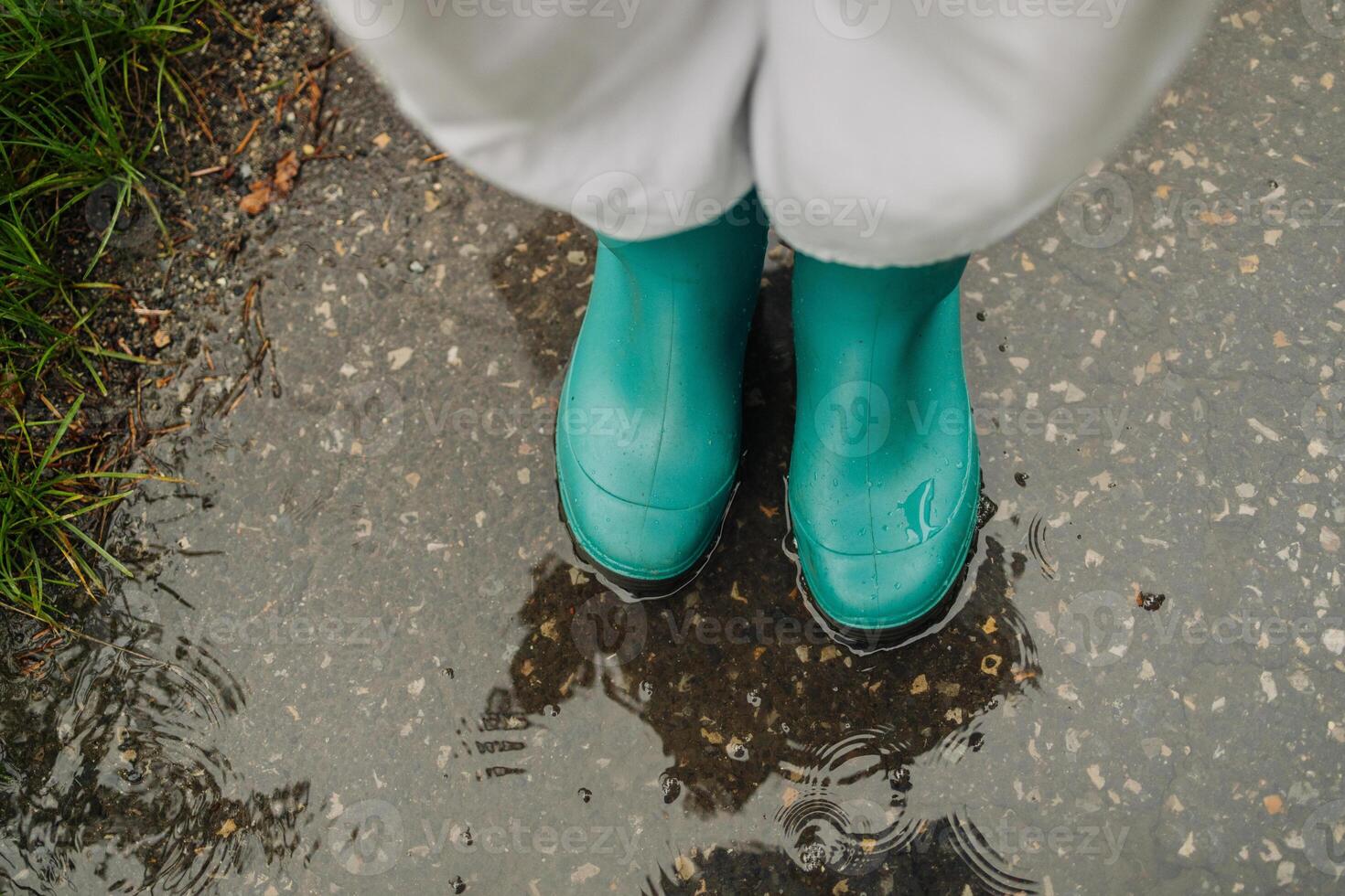 Autumn fall concept with colorful leaves and rain boots outside. Close up of woman feet walking in blue boots. photo