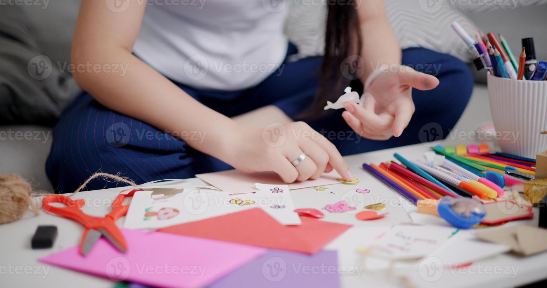 Selective focus, Hands of Young Asian woman sitting on sofa decorating a greeting card in the living room, Holiday hobbies, crafts, DIY cards photo