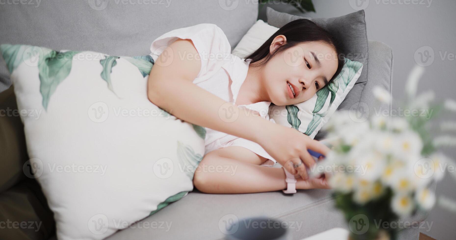 High angle view, Carefree young woman lying on sofa and playing social media by smartphone in the living room at home ,Lifestyle with device technology photo