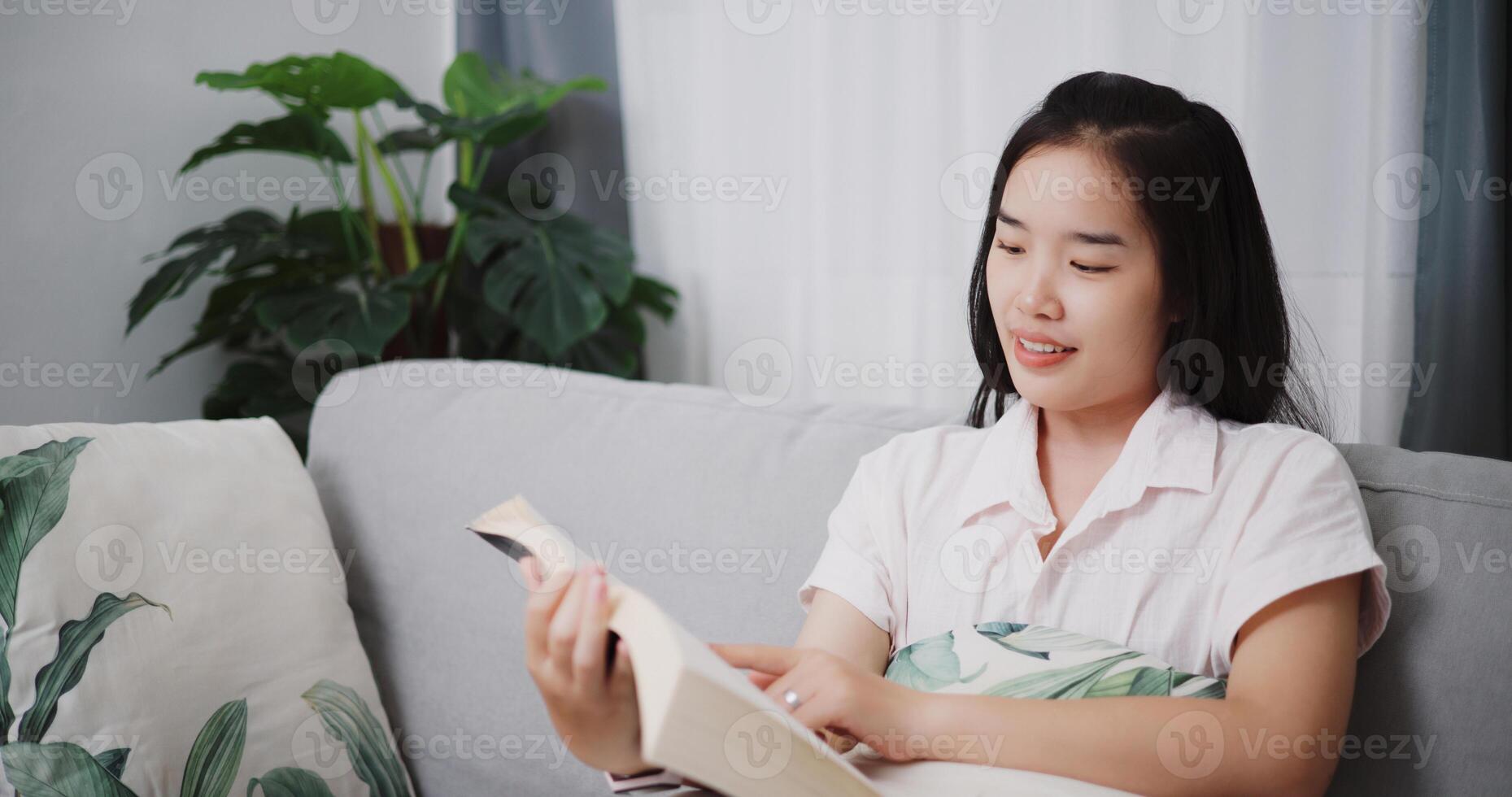 Portrait of Carefree young woman reading a book on sofa in the living room ,Enjoying a quiet time and relaxing cozy home photo