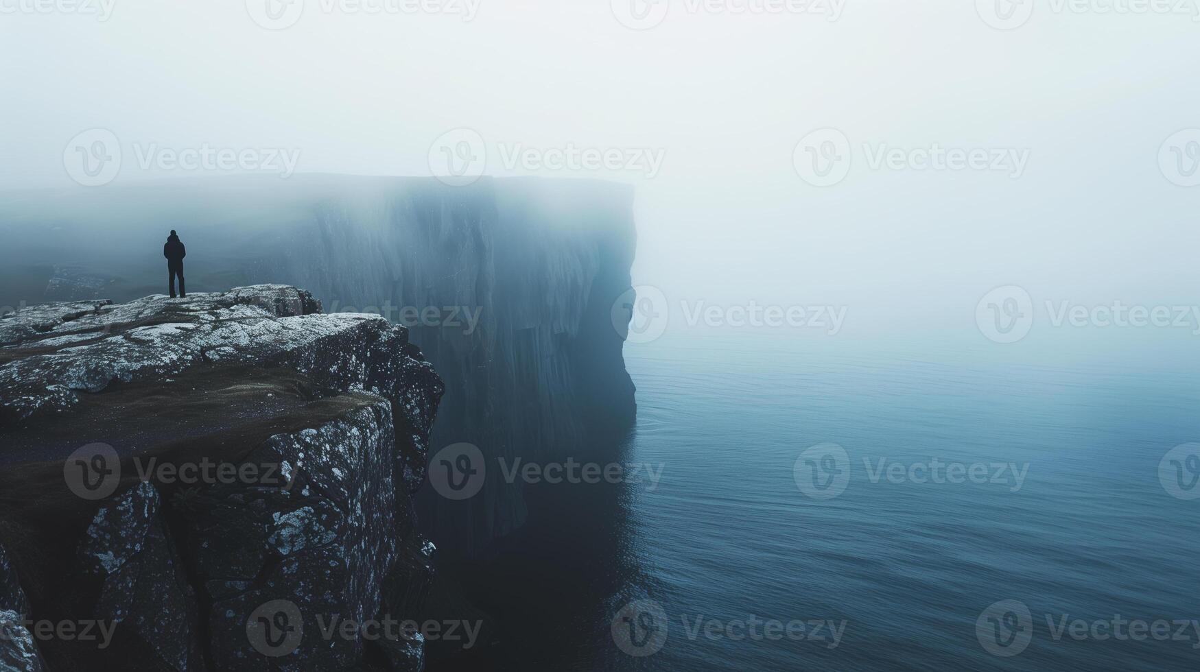 A solitary figure contemplating a misty cliff overlooking the serene waters photo