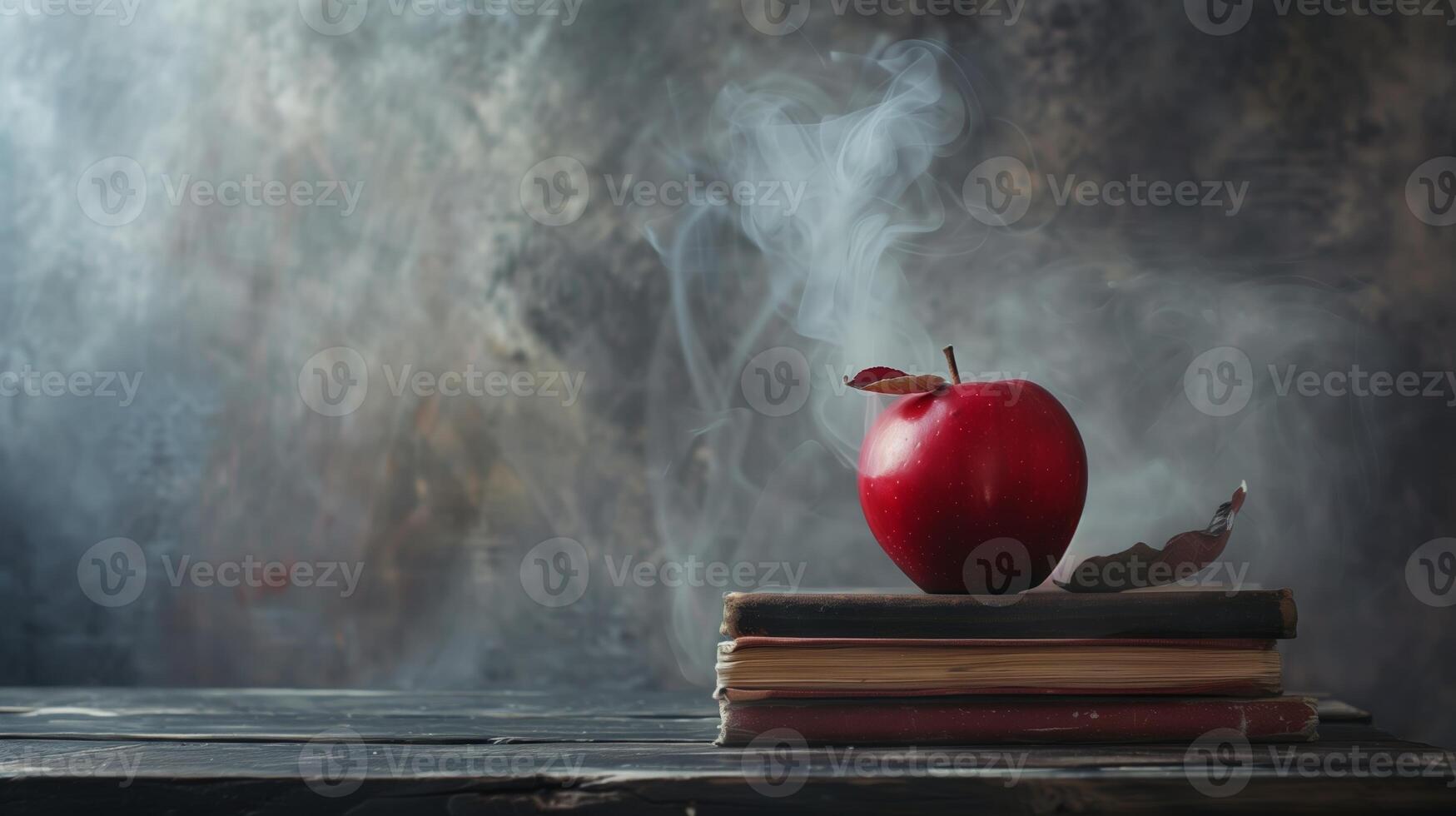 A red apple sitting on top of a stack of books on top of a black table photo