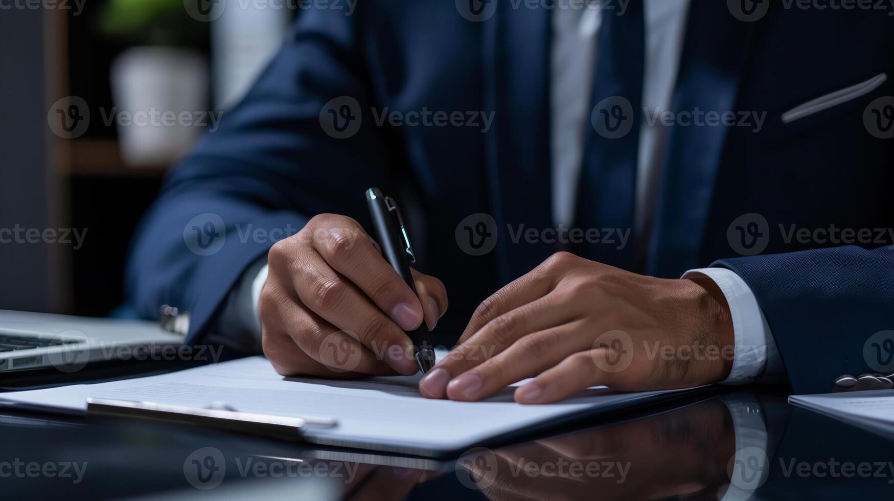 Close-up of a businessman in a suit signing a document at a desk photo