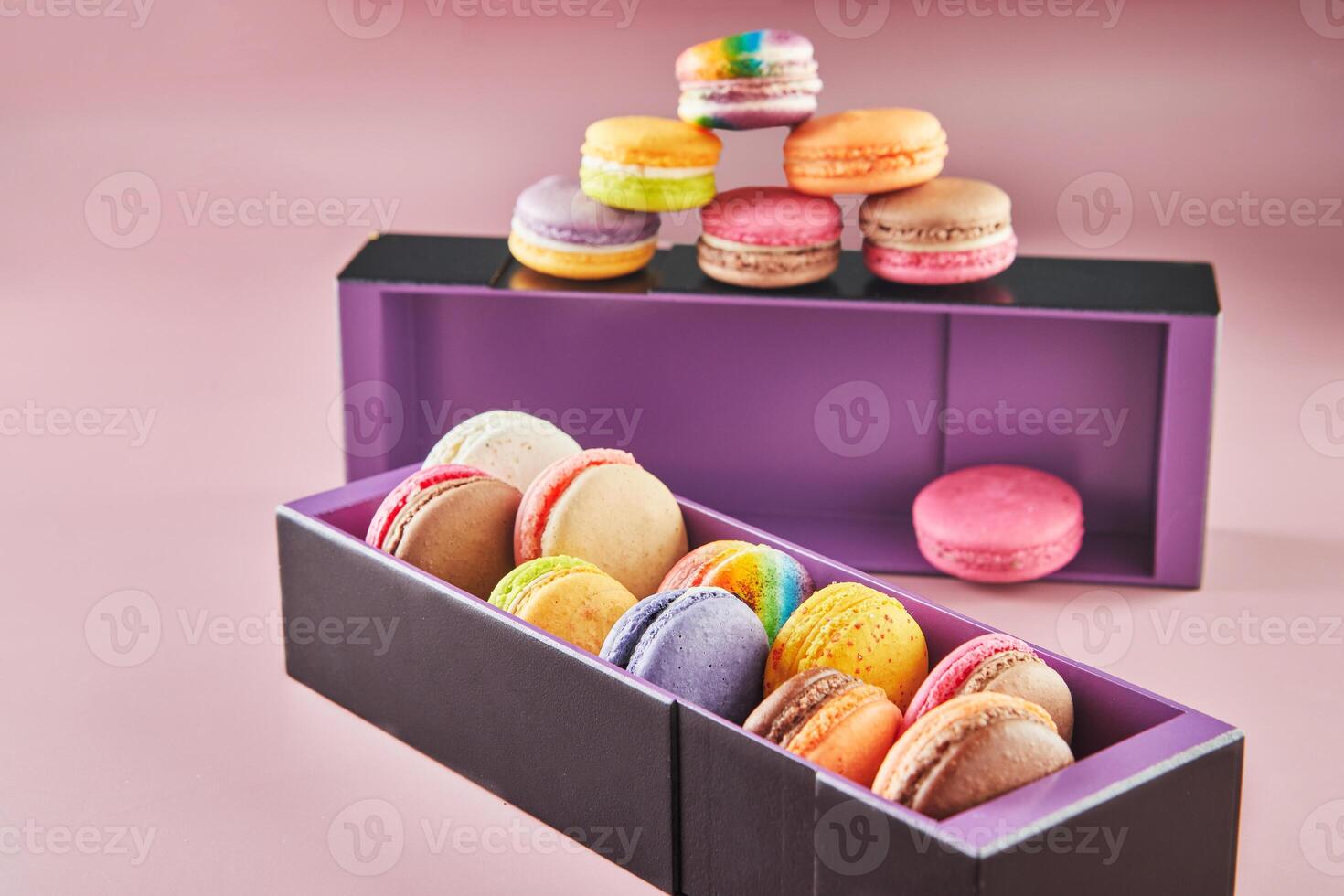 Colorful macarons of different flavors in boxes on a pink background with shadow photo