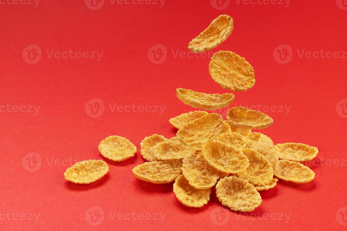 Falling corn flakes isolated on red color background, full depth of field photo