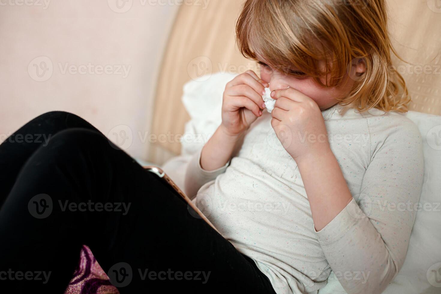 Sick little girl with a cold sneezing into a tissue photo