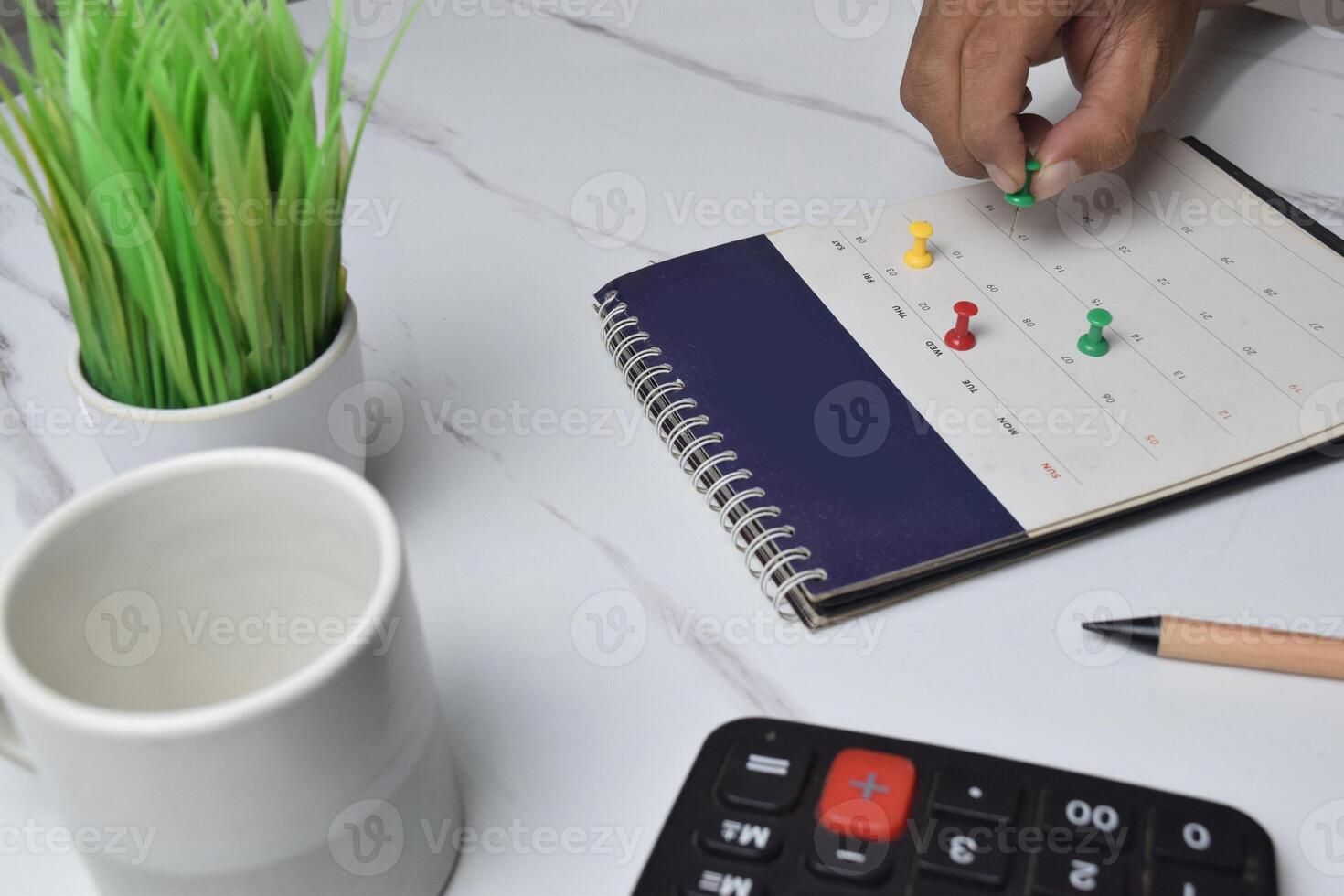 View of hand use pushpin on calendar to booking about date and time of meeting for day off vacation photo