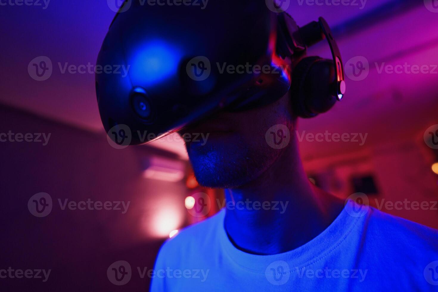 A player plays a game using a virtual reality helmet in a neon room. Close-up photo. photo