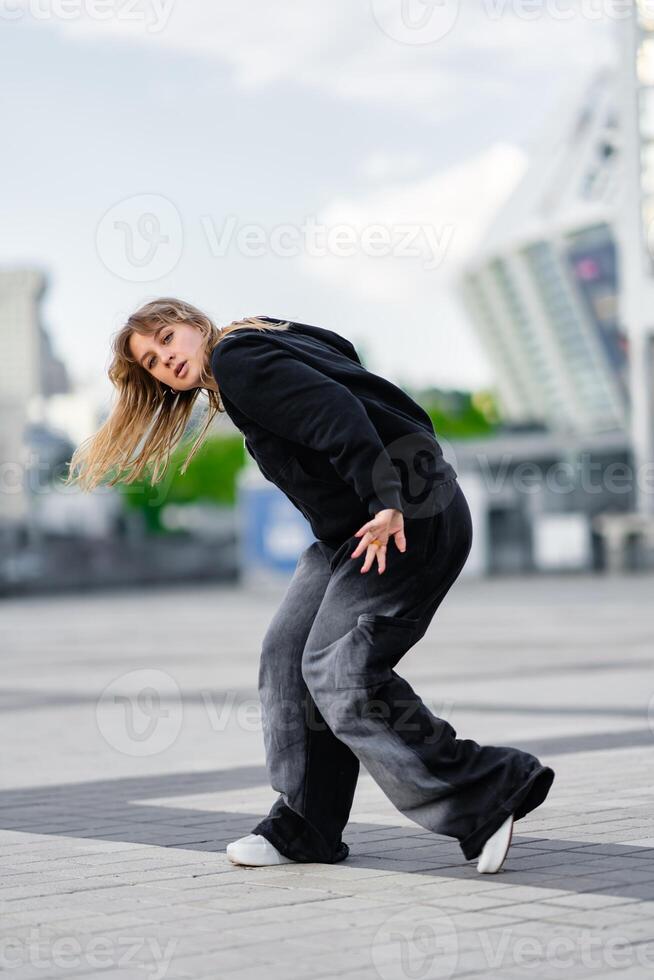 A young woman wears oversized clothes and dances hip-hop. photo