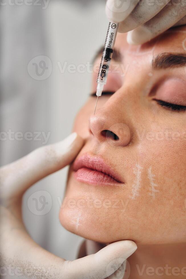 Injections into the skin of the face. A woman came to the clinic for facial skin care. photo