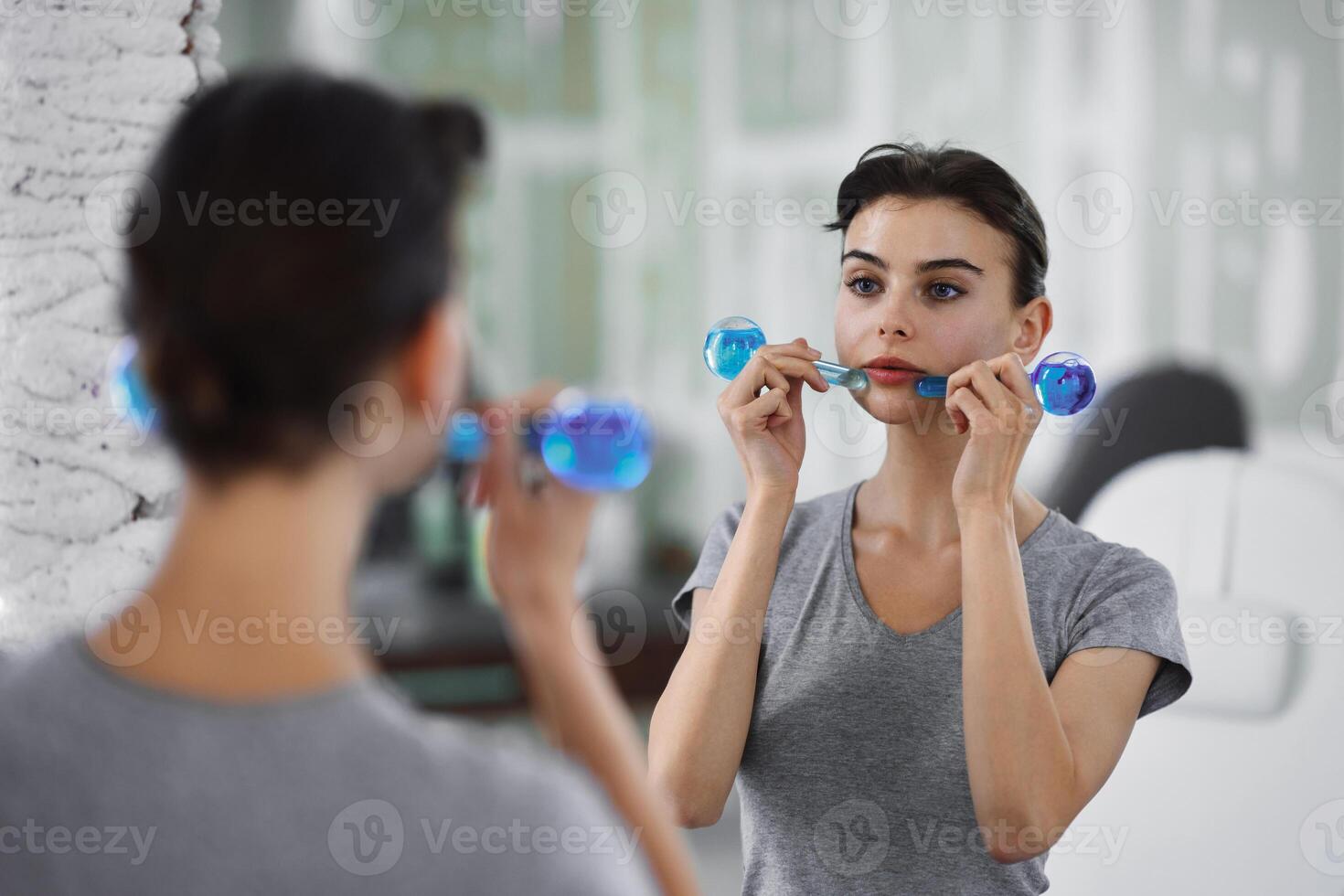 Facial skin care. A woman is doing a face massage using ice spheres. photo