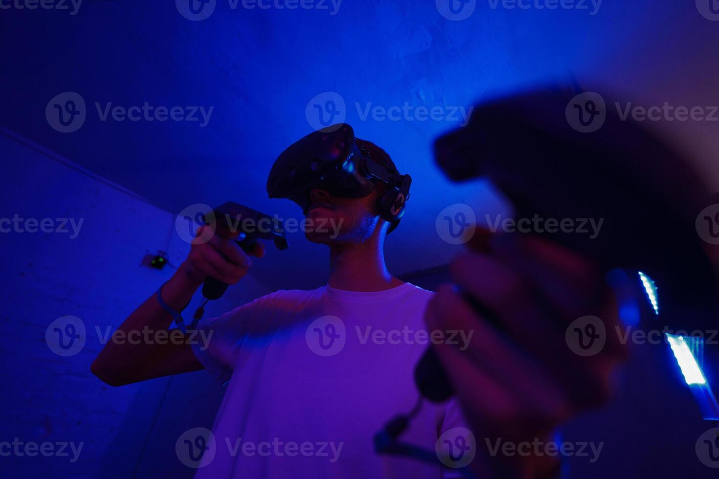 A player plays a game using a virtual reality helmet in a neon room. Close-up photo. photo