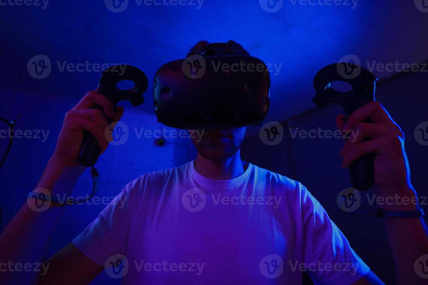 A player plays a game using a virtual reality helmet in a neon room. Close-up photo. photo