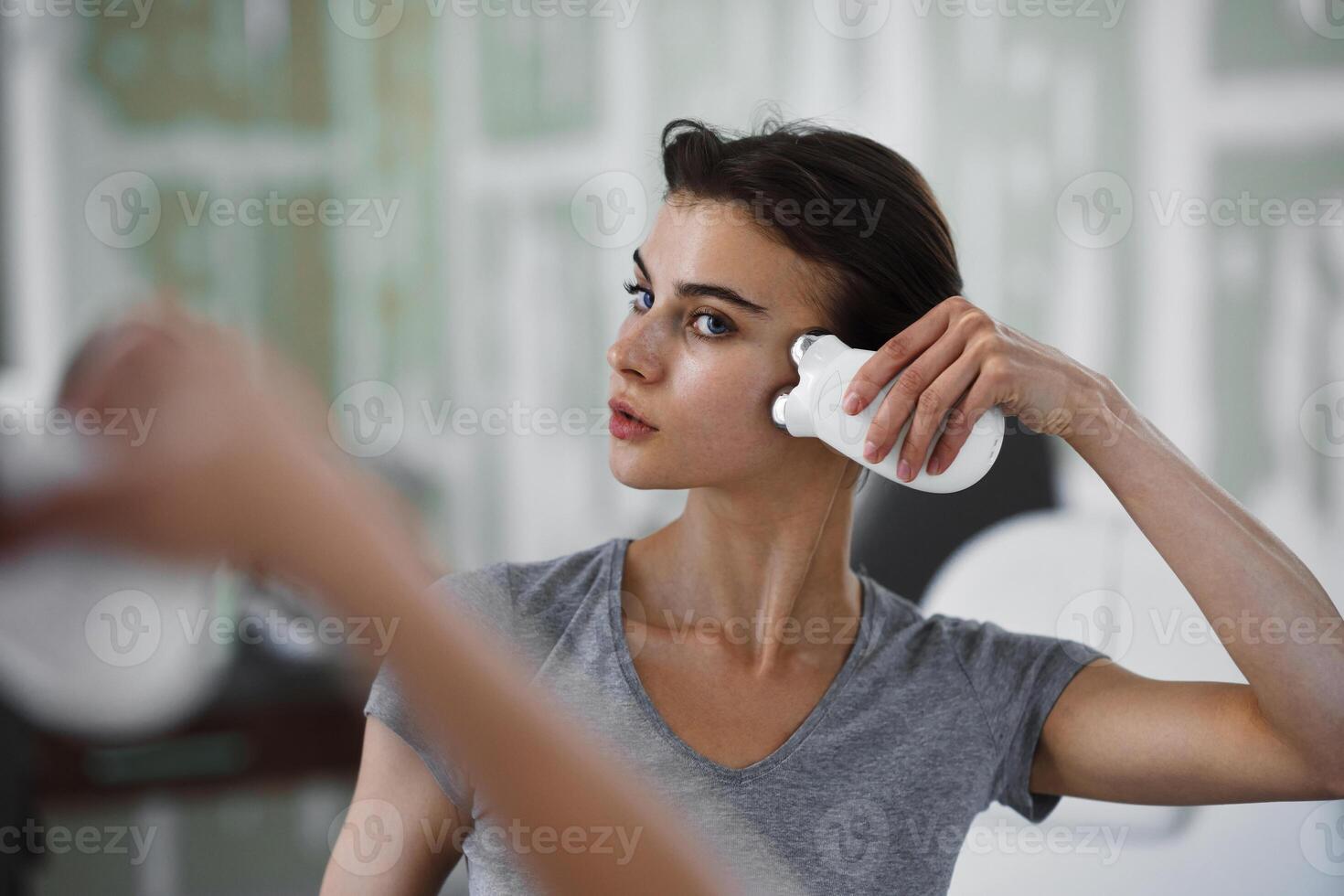 Facial skin care. A woman is doing a face massage using a massager that passes micro current. photo