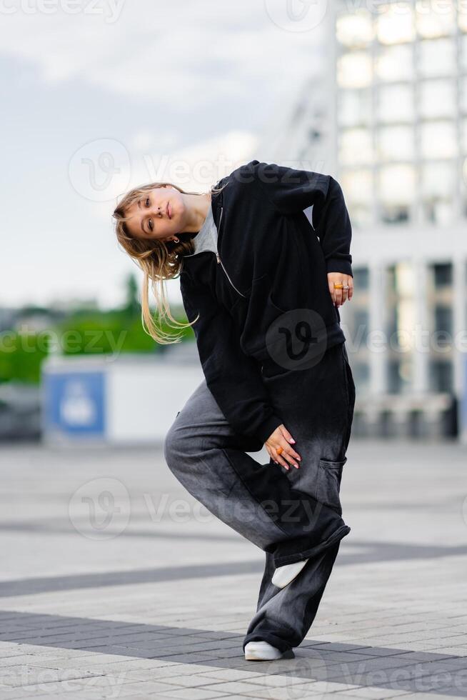 A young woman wears oversized clothes and dances hip-hop. photo