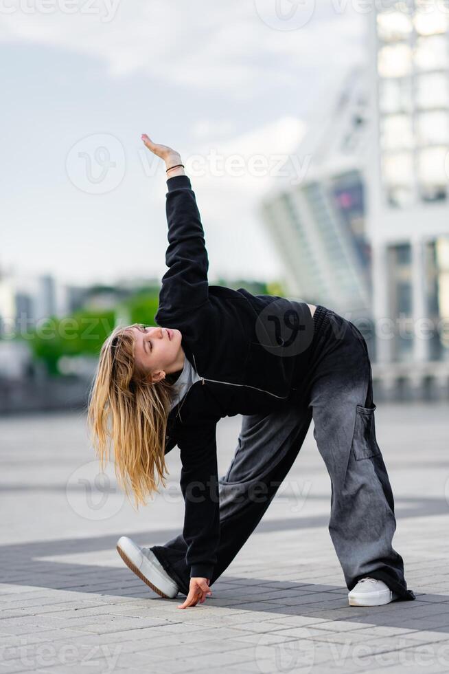 A young woman wears oversized clothes and dances hip-hop. photo