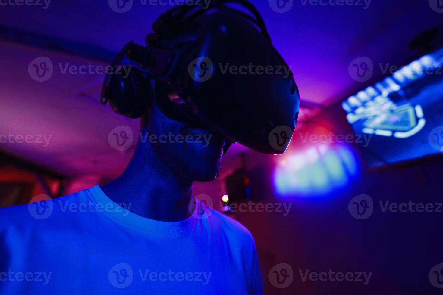 A player plays a game using a virtual reality helmet in a neon room. Close-up photo. photo