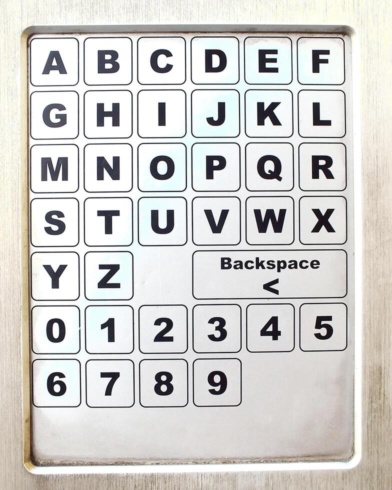 close up of a metal keypad number and alphabet on a public facility. unclean metal object photo