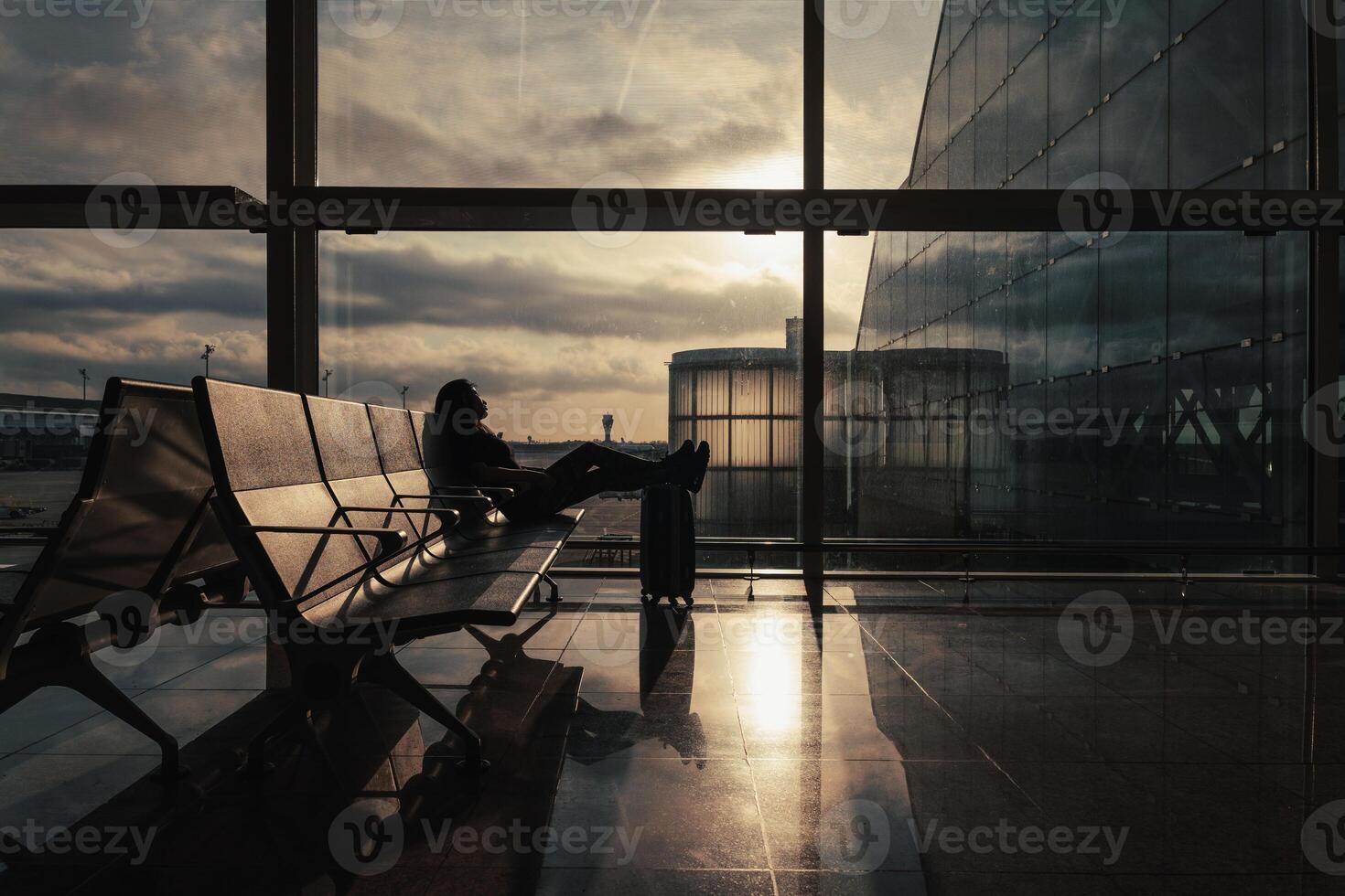 Rays of the sun enter through the window of the boarding area and illuminate the passenger waiting for her flight. photo