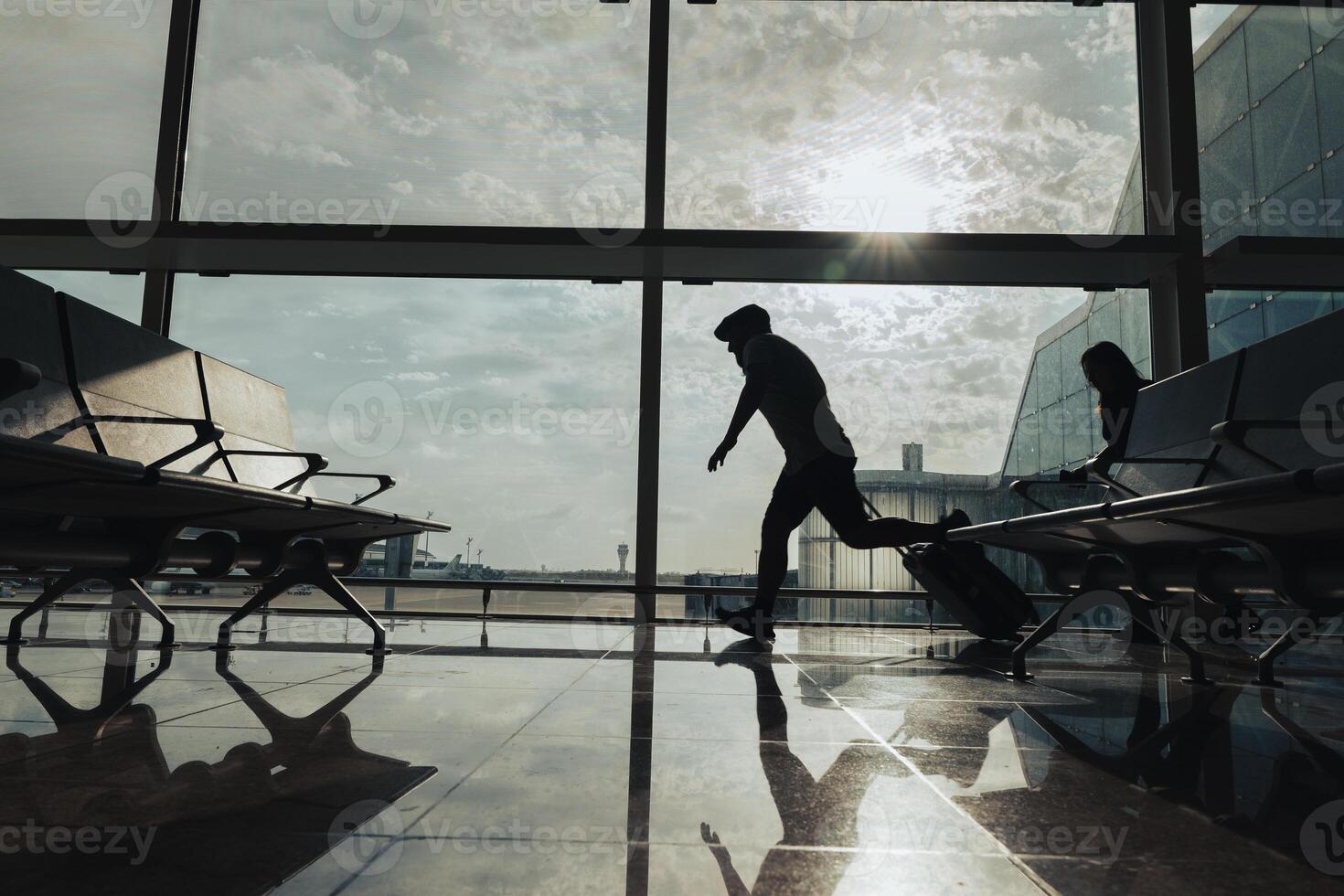 A couple runs with a suitcase through the airport boarding area to avoid missing their flight. photo