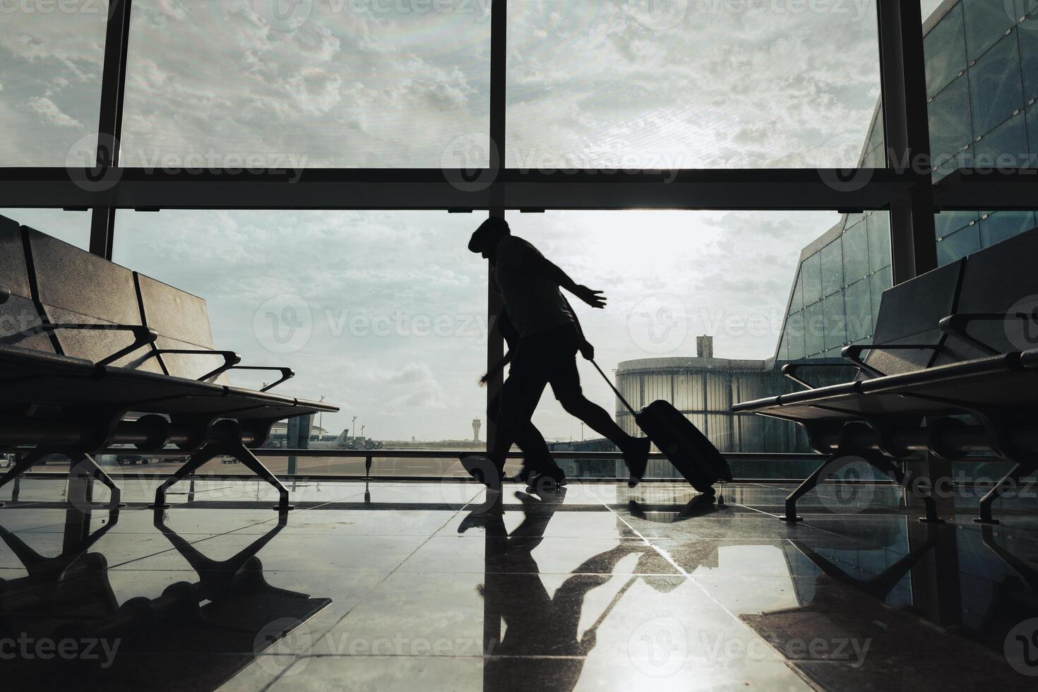 A couple runs with a suitcase through the airport boarding area to avoid missing their flight. photo