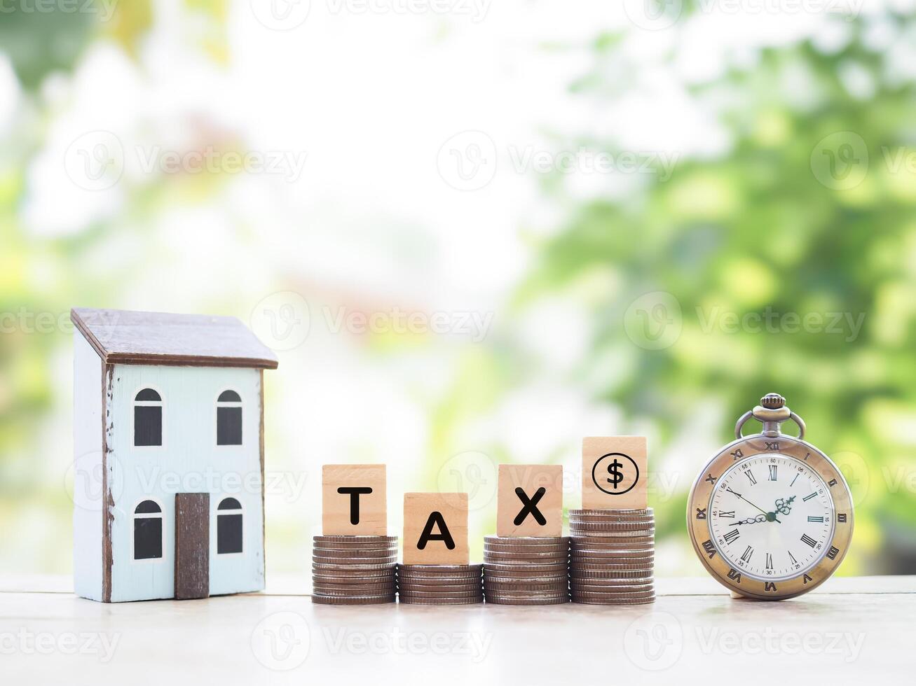 Vintage watch, Miniature house and Wooden blocks with the word TAX on stack of coins. The concept of payment tax for house, manage time to success, Property investment, House mortgage, Real estate photo