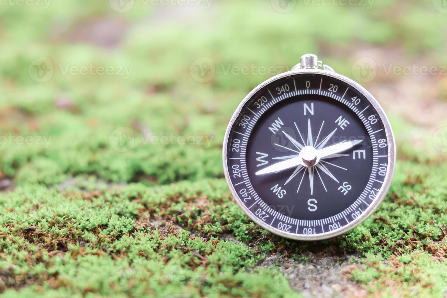 Compass with green moss background. The concept of world tourism day, Searching the right directions and Travel photo