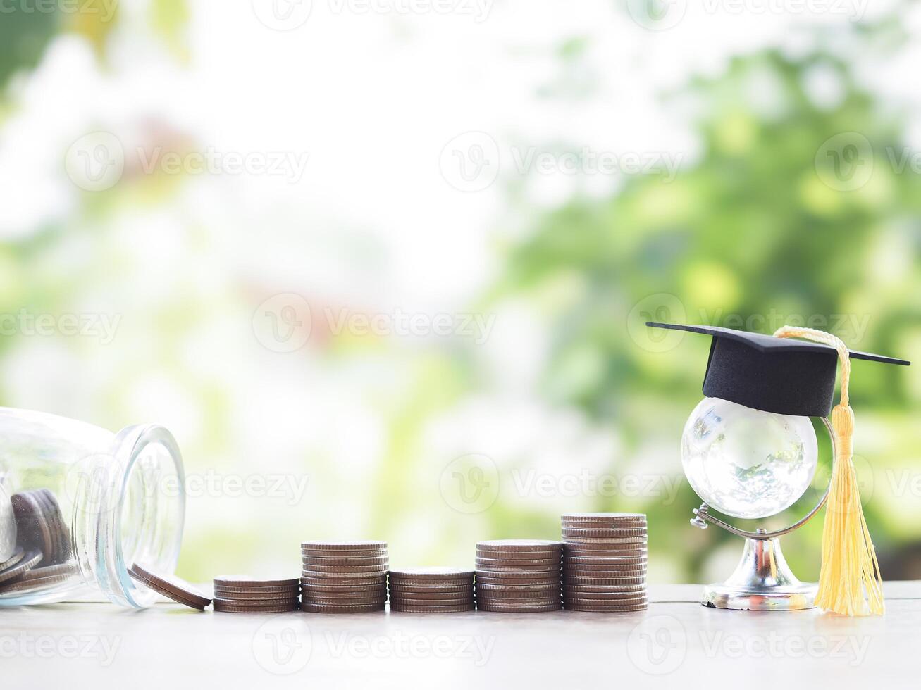 Glass earth globe with graduation hat, stack of coins. The concept of saving money for education, student loan, scholarship, tuition fees in the future photo
