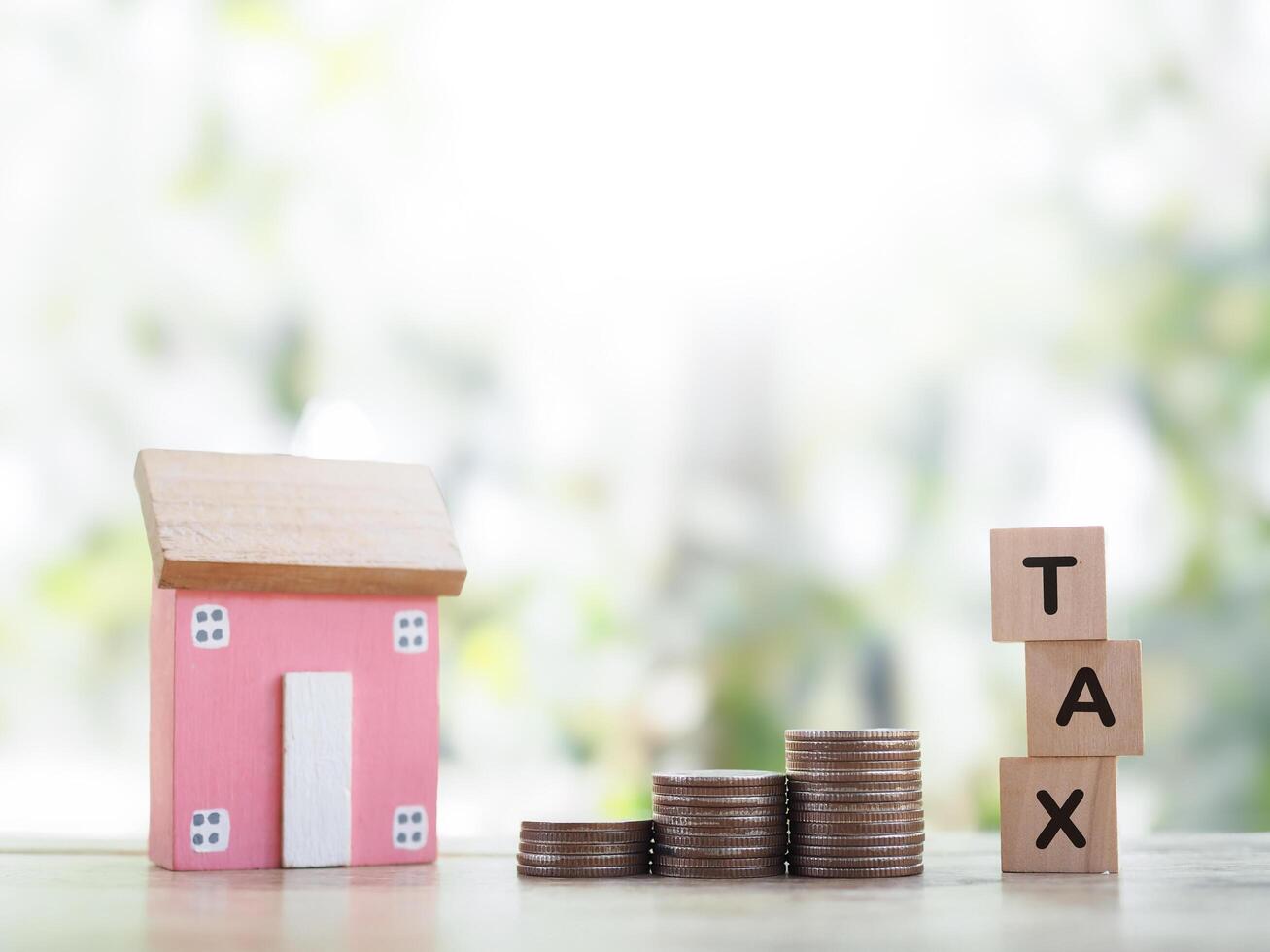 Miniature house, Wooden blocks with the word TAX and stack of coins. The concept of payment tax for house, Property investment, House mortgage, Real estate photo