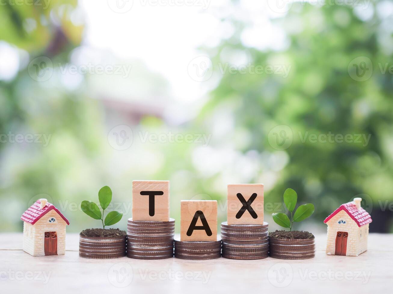 Miniature house and Wooden blocks with the word TAX on stack of coins. The concept of payment tax for house, Property investment, House mortgage, Real estate photo