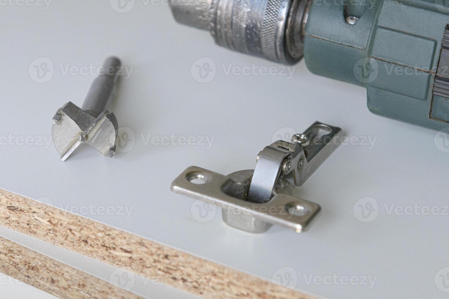 Special drill for large holes in wood. Tools for installation furniture fittings. hinge fixed on a modern cabinet. photo
