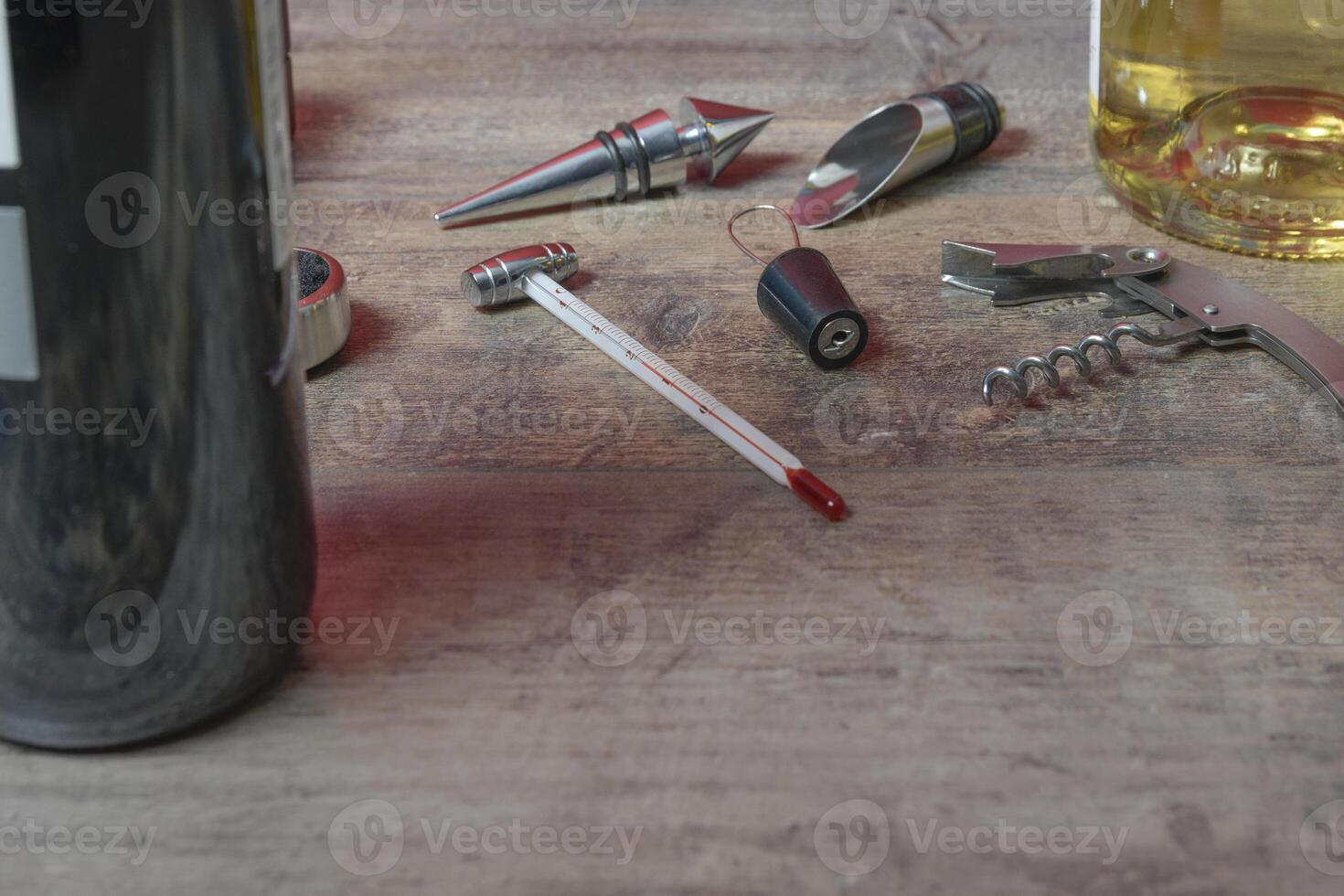 Bottled wine set from accessories. Additional stoppers, means for opening, a corkscrew and thermometer. On the texture table. Close-up. photo