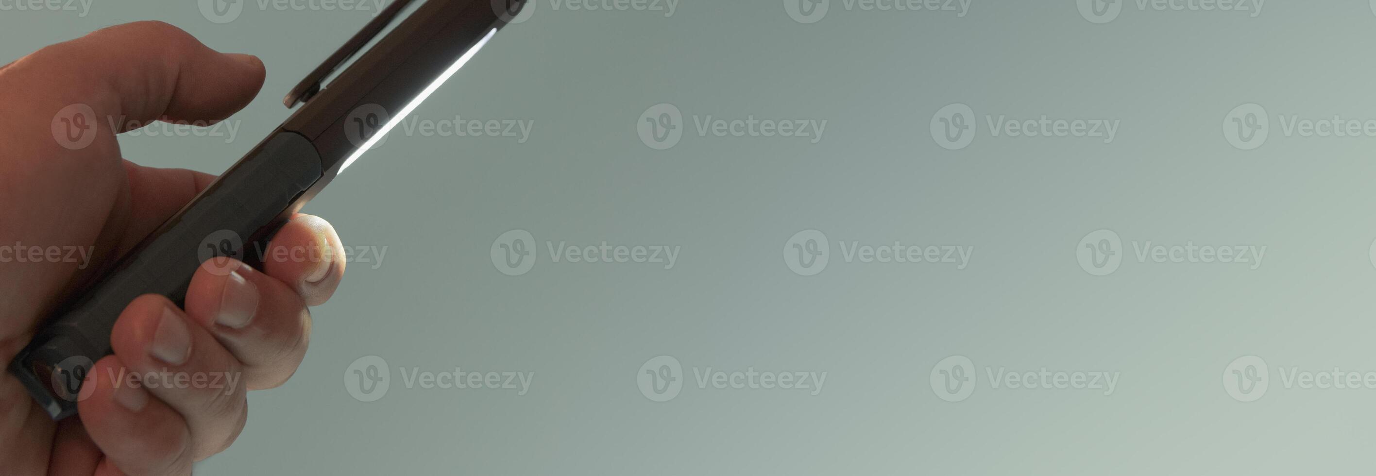 Pocket led flashlight in hand. illuminates blue background. Copy space. Banner photo