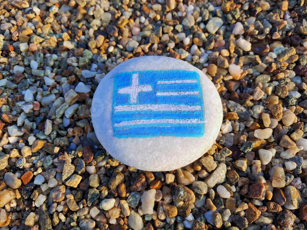 Greece country flag painted on the sea stone on pebble beach background close-up. Vacation concept. photo