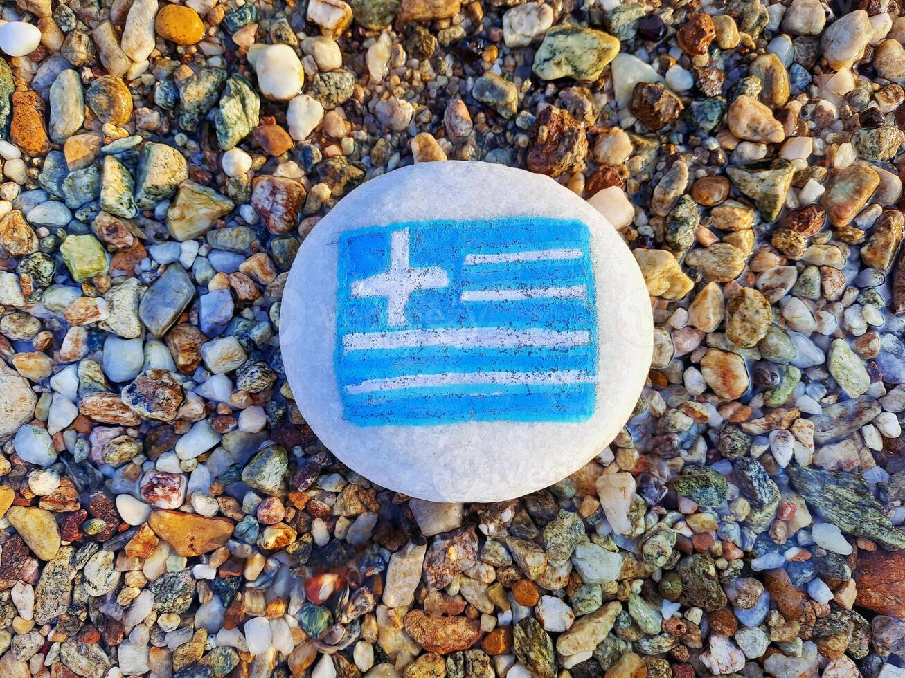 Greece country flag painted on the sea stone on pebble beach background close-up. Vacation concept. photo