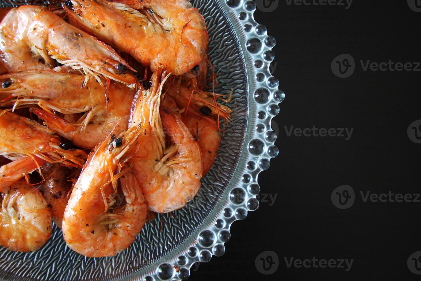 Closeup of cooked shrimp in a glass bowl on a black background. photo