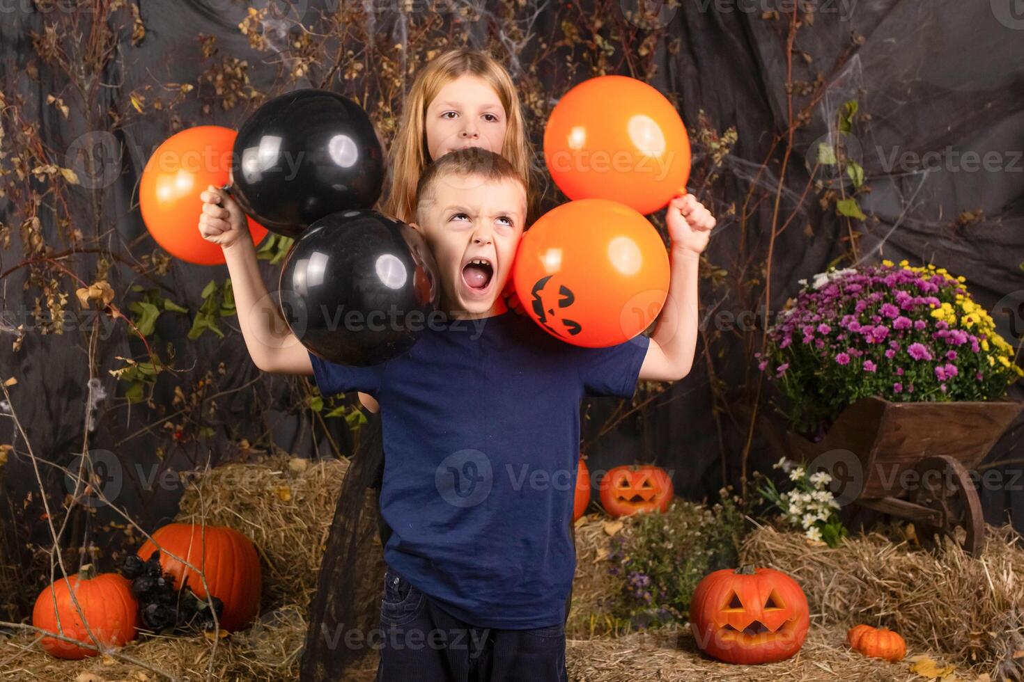 close-up portrait of happy, funny children holding a pumpkin on their heads. children playing preparation for halloween photo