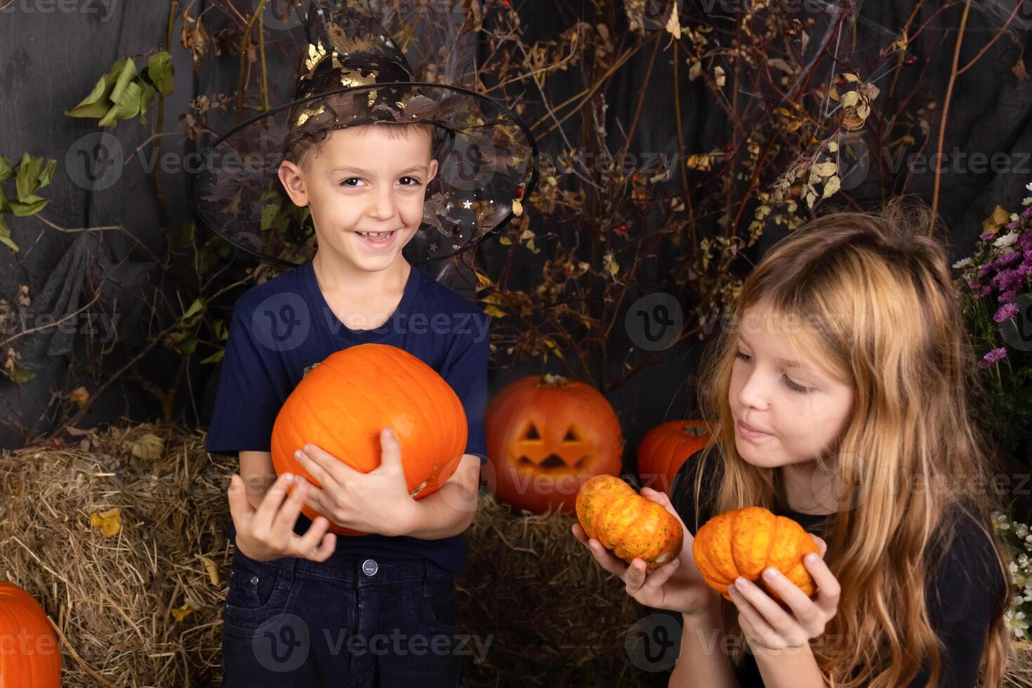 close-up portrait of happy, funny boy and a girl playing with pumpkin. children playing and preparation for halloween photo