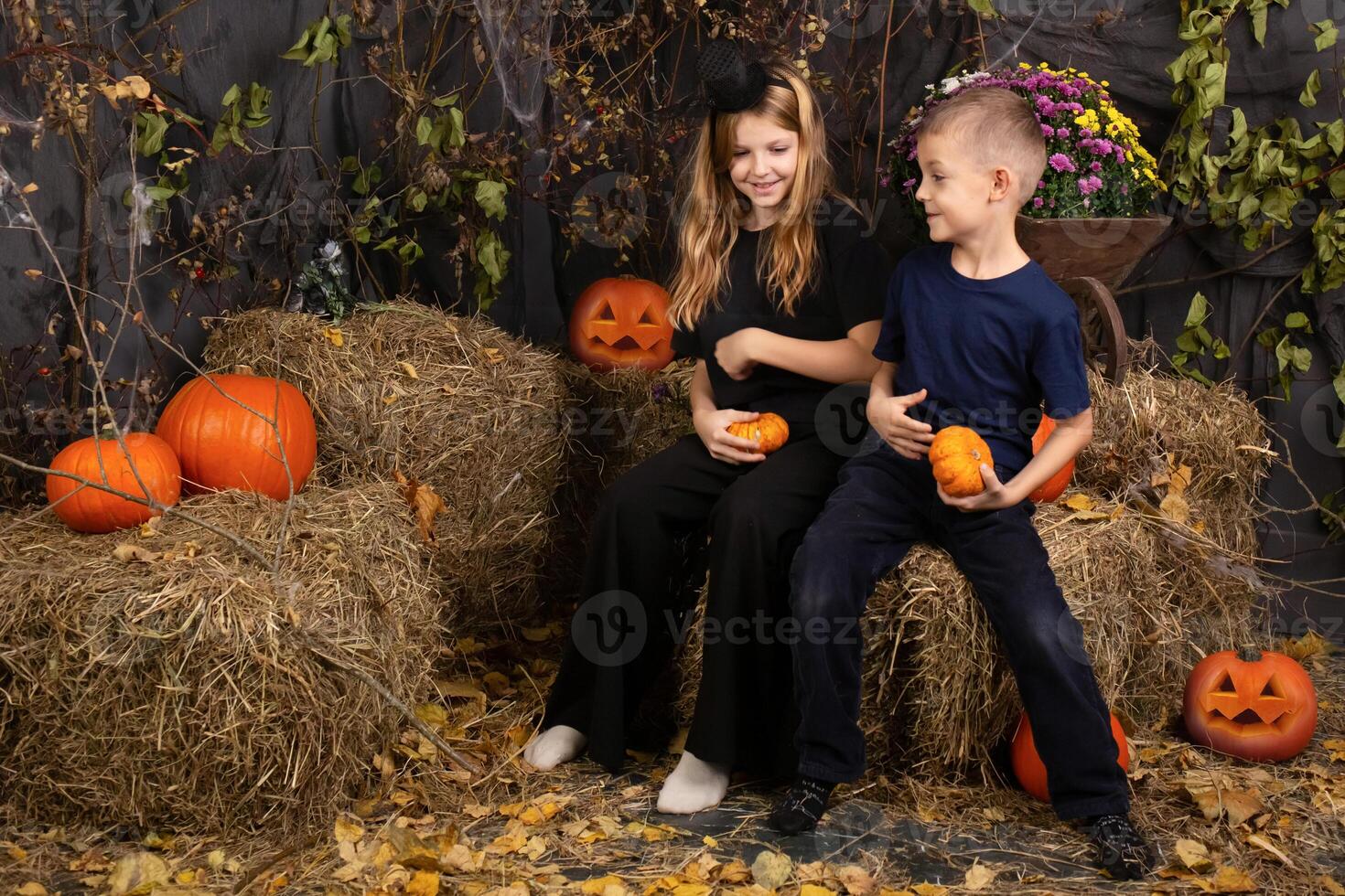 Happy brother and sister on Halloween. Funny children in carnival costumes indoors. Cheerful children play with pumpkins photo