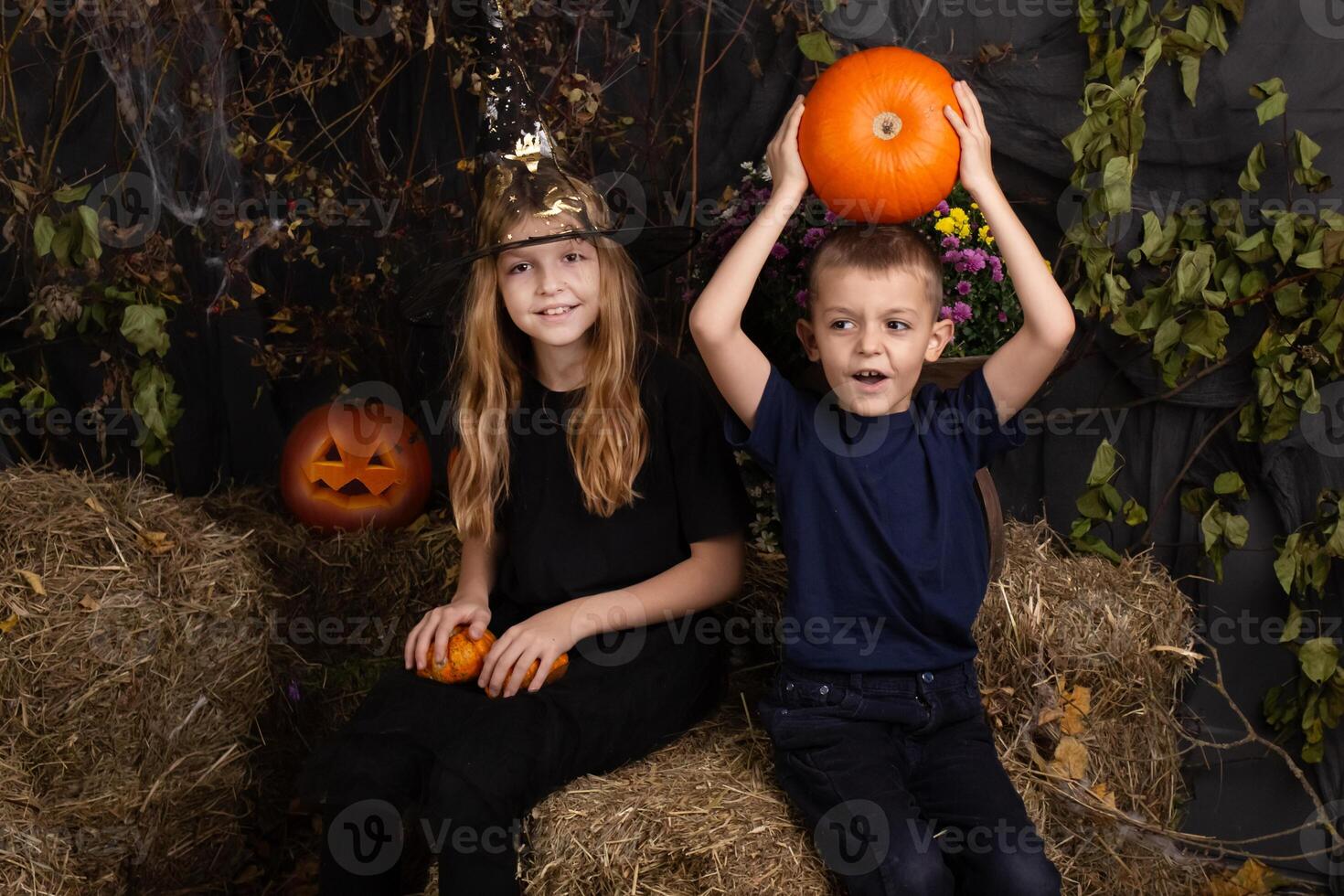 Happy brother and sister on Halloween. Funny children in carnival costumes indoors. Cheerful children play with pumpkins photo
