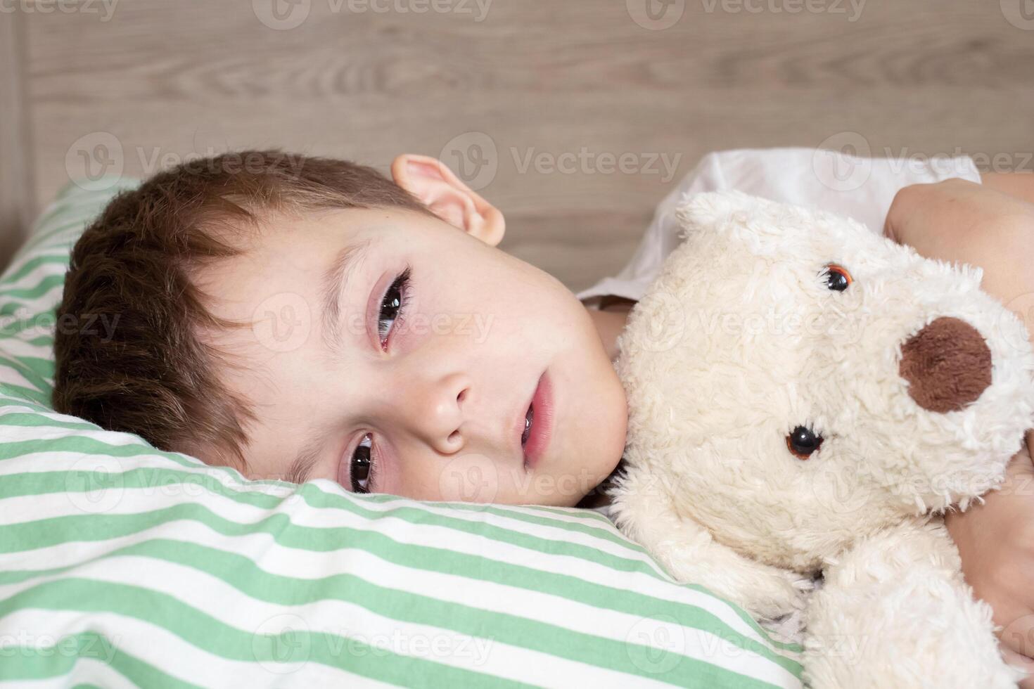 Unhealthy little boy child sleep in bed relax at home in bedroom. Sick ill little kid suffer from flu fever asleep in bed on lockdown quarantine photo