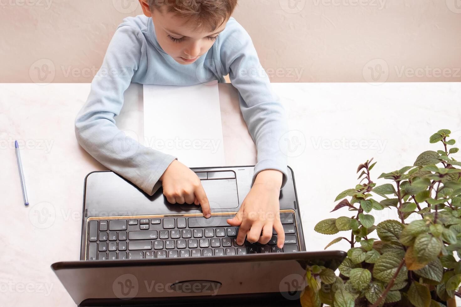 close-up top view, a child in a blue sweater learns to type on a computer, laptop. teaching people at home in bedroom, studying online on computer photo