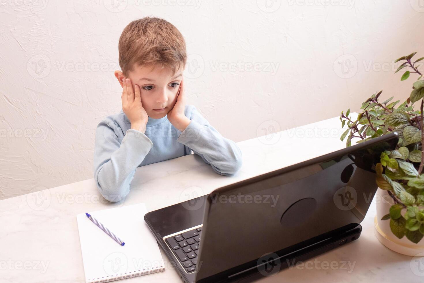 A little boy is very surprised in a virtual classroom. School at home. little cute boy takes an online lesson. the child studies at home. concept of safe online education photo
