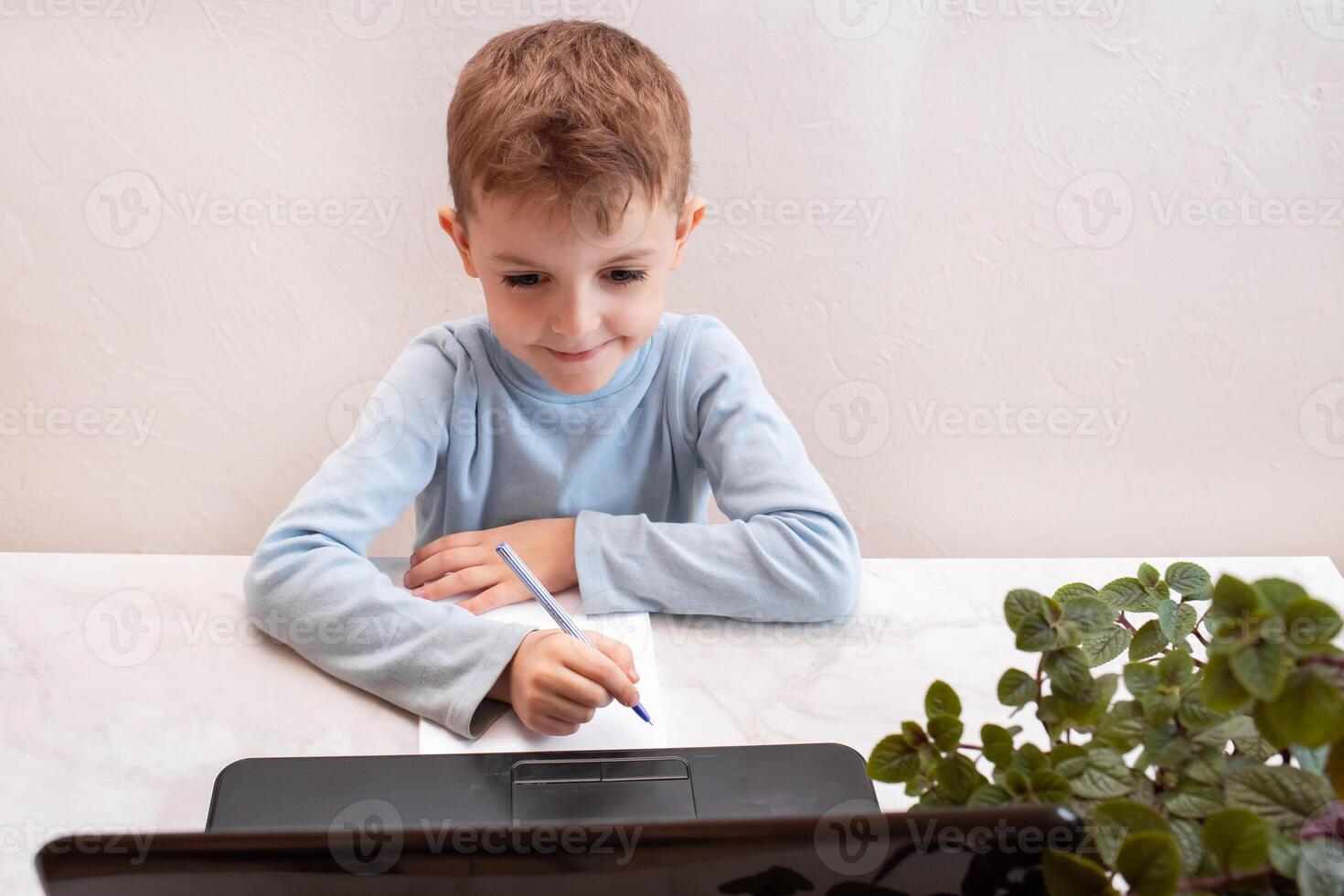 close-up top view, a child in a blue sweater learns to type on a computer, laptop. teaching people at home in bedroom, studying online on computer photo